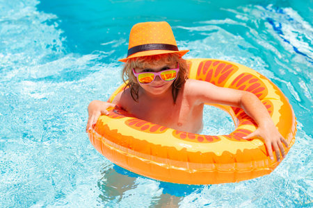Fun child portrait. Boy kid swimming and playing in a pool. Child playing in swim pool. Summer...