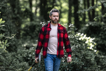 Man or lumberjack in checkered shirt hold axe. Lumberjack or woodman. Man strong attractive guy...