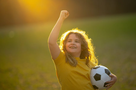 Happy child playing soccer. Kid boy kicking a football on the grass. Kid running with a soccer ball. Playful children enjoying a football game. Kids soccer match. Kid playing football kicking a ball.の写真素材