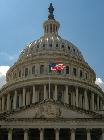 American flag waving on a flagpole against Congress and clear blue sky. US flag fluttering in the wind near Congress. USA, US waving flag, American flag.の写真素材