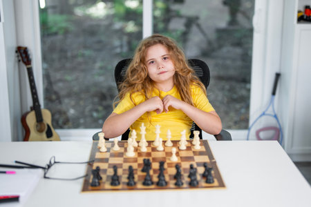 Kid playing chess at home. Child thinking over chess move. Kids learn strategy with chess. Kid concentrating on chessboard. Teen studying chess game. Thoughtful child playing chessgame at desk.の写真素材