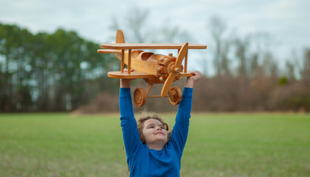 Happy child play with wooden plane outdoor. Child playing with toy airplane. The dream of becoming a...