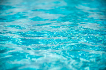Background of blue water in swimming pool with sun reflection, ripple water wave in pool. Clear...