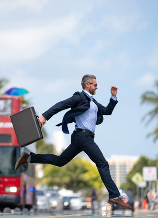 Busy rich businessman running to a meeting. Businessman run on road. Business man in a suit run to...