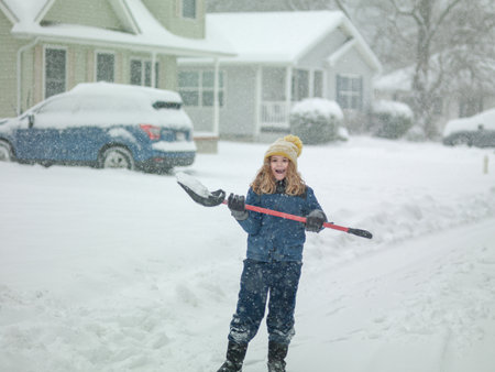 Child clearing sidewalks and shoveling snow. Child removing snow with shovel. Little helper. Winter kids fun outdoor. Little boy with a shovel to clear the snow. Winter season, snowy weather, cold.の写真素材