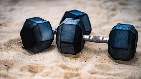 Sports equipment. Dumbbells background. Dumbbell on the beach for summer sport. Dumbbells in sand....