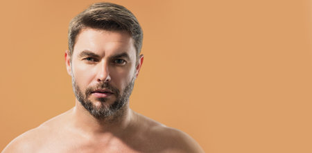 Beauty portrait of handsome man with moisturizing cream on face, isolated background. Skincare routine concept. Male beauty. Shaving, hair styling. Banner for header, copy space.の写真素材