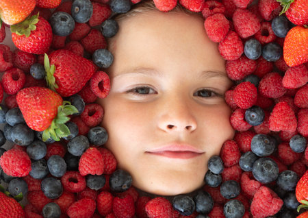 Summer fruits. Child face with berries mix of strawberry, blueberry, raspberry, blackberry.の写真素材