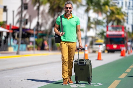 Traveling alone. Mature tourist on summer tropical street. Travel through the city. Man with traveling bag. Summer travel. Travel journey. Summer is the perfect time for travel. Traveling people.の写真素材