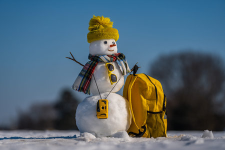 Snowman with luggage ready for holiday trip. Winter vacation starts with snowman. Christmas snowman...