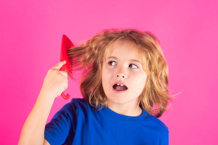 Comb and hair brush concept. Morning kids after shower. Child with curly hair hold hairbrush or comb. Healthy hair. Kid brushing unruly tangled hair.の写真素材