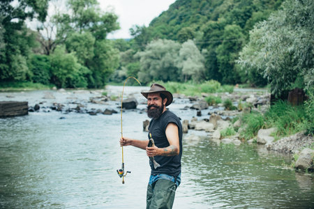Fishing hobby and summer weekend. Bearded men fisher with fishing rod and net.の写真素材
