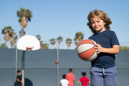 Child playing basketball on outdoor court. Happy child boy hold basketball ball. Summer sport kids. Child on basketball game. Sporty child training basketball. Outdoor sport for children.の写真素材