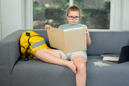 Child enjoying book in cozy room. Kid reading big book with smile. Clever student holding open book....