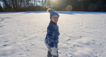Winter child. Funny child playing in the snow. Kid play in snowy winter park. Winter fun with...