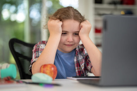 Kid learning at home with laptop and books. Child learn online using laptop at desk. Learning with...
