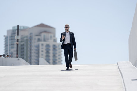 Rich business man walking outdoors. Successful business man with briefcase. Leader on the move. Business man walking confidently. Businessman in a suit going to work. Business professional in motion.の写真素材