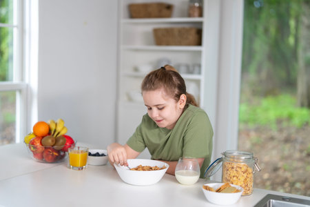 Child eating healthy breakfast at home kitchen. Kid at the kitchen dining table. Happy kid having...