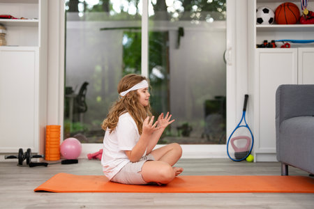 Kid doing sport fitness at home. Fit kid exercising at home. Kid practicing fitness at home. Child stretching body for healthy lifestyle. Child enjoying sport fitness at home. Child workout fitness.の写真素材