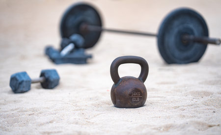 Kettlebell and weights background. Bodybuilding with heavy weights. Park workout with dumbbells. Sports scene with weights. Kettlebell, dumbbells and barbell background. Weights training on the beach.の写真素材