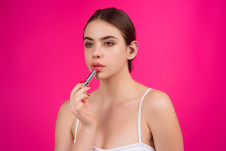 Photo of shirtless woman posing with lipstick, isolated studio background. Beautiful woman holding with naked shoulder hold lipstick. Sexy girl using lipstick.の写真素材