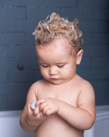 Todler in shower, infant in shower. Funny happy baby bathes in bathtub with water and foam. Kids hygiene.の写真素材