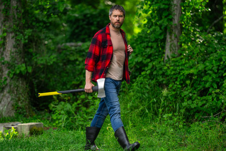 Hard working man with axe in forest. A bearded lumberjack with a large ax. Portrait of a bearded man...