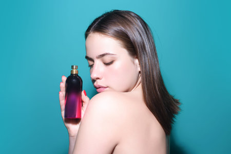 Woman with perfume bottle in studio. Girl with perfume, young beautiful woman holding bottle of...