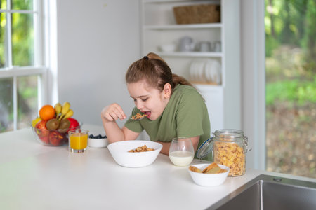 Kid eating healthy breakfast at home. Kid enjoying fresh fruits at the dining table.の写真素材
