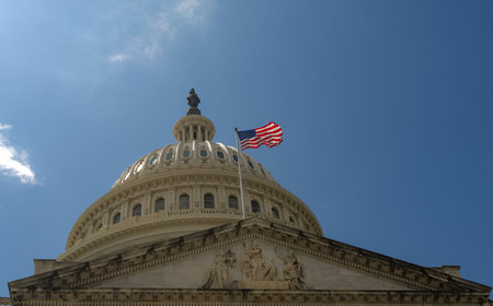 Waving American flag. Washington DC Capitol with American flag closeup. American flag over Congress. Famous landmark in the capital with American flag.の写真素材