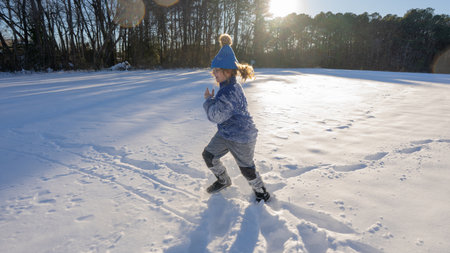 Kid in snowy winter park. Winter child plays with snowflakes. Winter holidays is fun. Childhood moments in winter. Portrait of kid in wintertime. Frozen fun on Christmas vacation.の写真素材