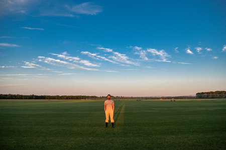 A farmer is walking through the farm. The man is watering the plants in the farm field. Irrigation system in action on the farm. The farmer in the farm field. Agricultural worker. Rural worker outdoors.の写真素材