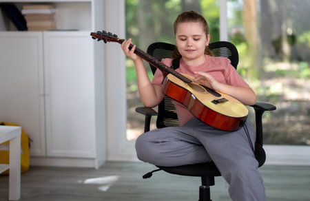 Kid playing guitar. Child practicing guitar music in living room. Kid learning guitar indoors. Boy with guitars during music lesson. Kid playing acoustic guitar. Child practicing songs.の写真素材