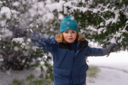 Snowball fun. Kid play snowball. Christmas holiday, Winter family vacation. Child enjoy Snowball fight. Kid in winter clothes throw snowballs. Kid in winter have fun playing with snow, make snowball.の写真素材