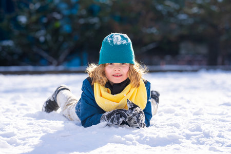Portrait of Child playing with snow, outdoors during snowfall. Winter child, outdoor portrait. Kid play in the snow. Kid play in snow park. Winter kid face. Kid teen boy in snow. Winter kids activity.の写真素材