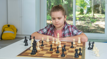 Child with chess at home. Child thinking on chessboard. Kid victory in chess match. Thoughtful child playing chess. Young chess player at home.の写真素材