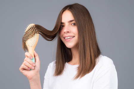 Young woman combing healthy and natural shiny hair, isolated on studio. Beauty hair care.の写真素材