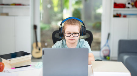 Kid reading books and writing homework in home school environment. Homeschool education helping...