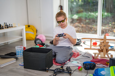 Child cleaning toys in playroom. Kid cleaning scattered toys on the floor. Kid cleaning children messy room. Teen cleaning untidy playroom interior. Kid picking up toys in messy room.の写真素材