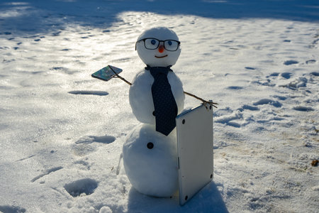 Snowman with mobile phone and laptop during winter celebration. Snowman working online in winter....