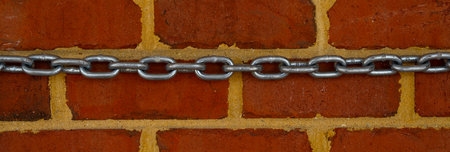 Chain on brick wall, vintage texture. Red brick wall for construction themes. Brick wall background. Textured bricks for design projects. Solid bricks structure. Brick wall pattern.の写真素材