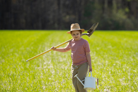 Spring garden. Kid digging soil with shovel. Child with tree plants in garden. Kids working in...