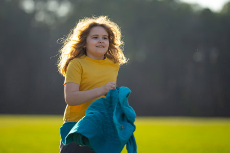 Child running on field. Happy kid running outdoors. Child jumping and running in nature. Kid running in a meadow. Summer fun for active child. Playful kid freedom. Free childhood in nature.の写真素材