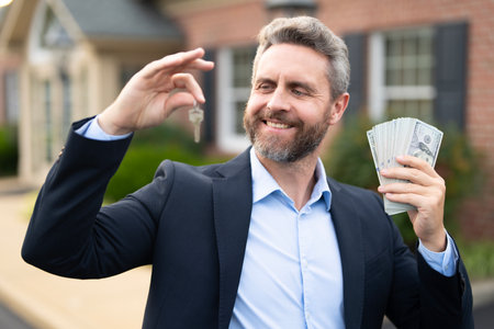 Real estate agent poses confidently in front of building ready for sale. Real estate entrepreneur closing deal. Mortgage agent buying a house. Realtor shows apartment. Business man near building.の写真素材