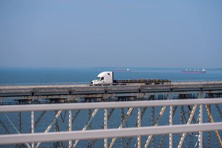 Truck driving across the bridge. Lorry transporting. Cargo trailer. Logistics truck, international shipment. Truck transport. Semi truck containers, logistics industry. Trucks lorry logistic concept.の写真素材