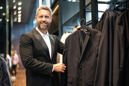Classic suit outfit. A hispanic businessman appreciates fine tailoring and suit. A well-dressed male model poses in a suit boutique. A retail assistant helps a stylish man find the perfect suit.の写真素材