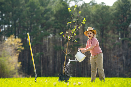 Kid with shovel in spring garden. Child cultivating a tree in garden.の写真素材