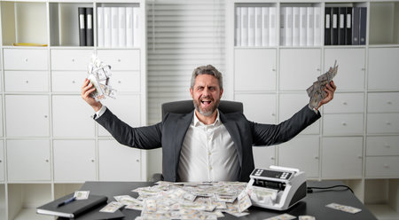 Businessman counting money at his office desk. Banker handling cash and bills in a corporate setting. Accountant organizing dollars and banknotes for finance management.の写真素材