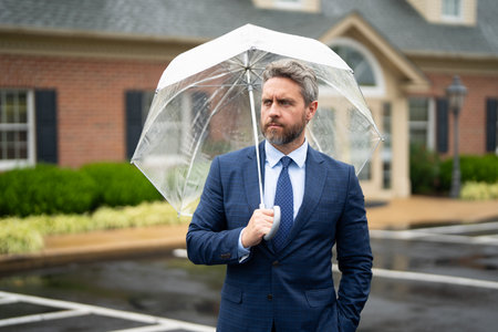 Businessman with umbrella in rain. Business patience. Businessman waiting in rain. Businessman on...