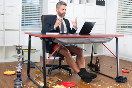 Funny business man during a video conference in messy office. Funny business concept. Funny online office. Fun business team online. Messy funny office workspace.の写真素材